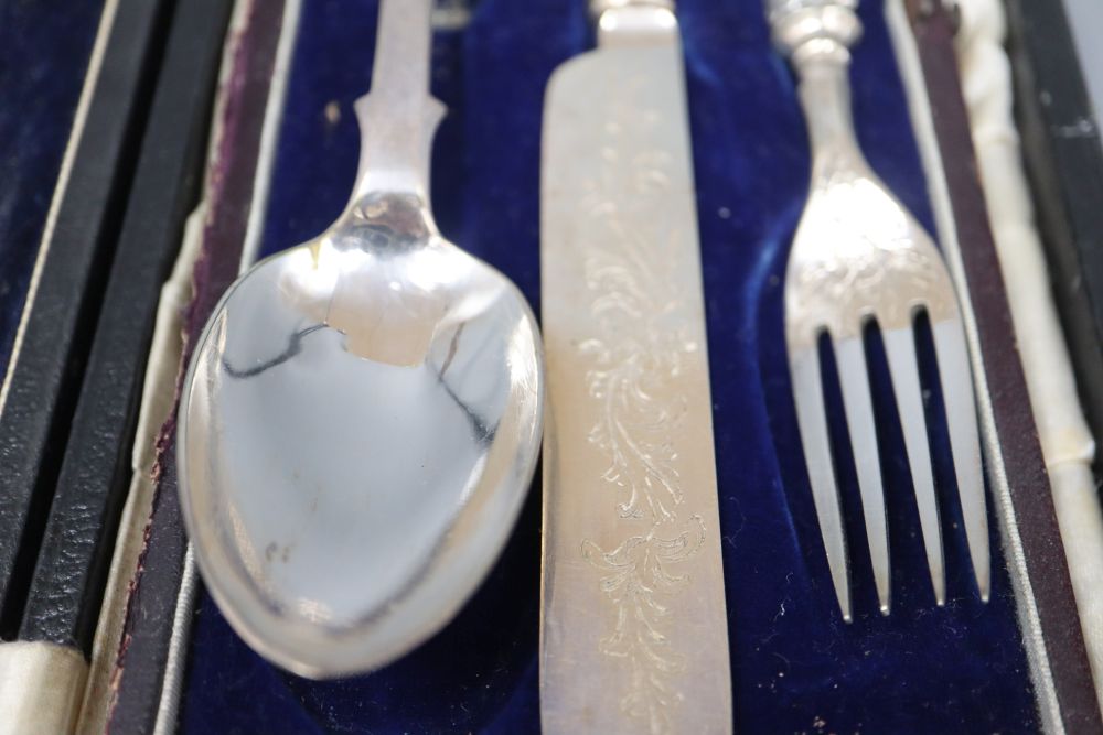 A cased Edwardian silver handled three piece carving set and a cased plated christening trio.